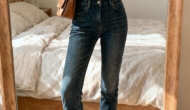 Person taking a mirror selfie in a bedroom, wearing a black puffer jacket, blue jeans, brown shearling boots, and a brown crossbody bag.